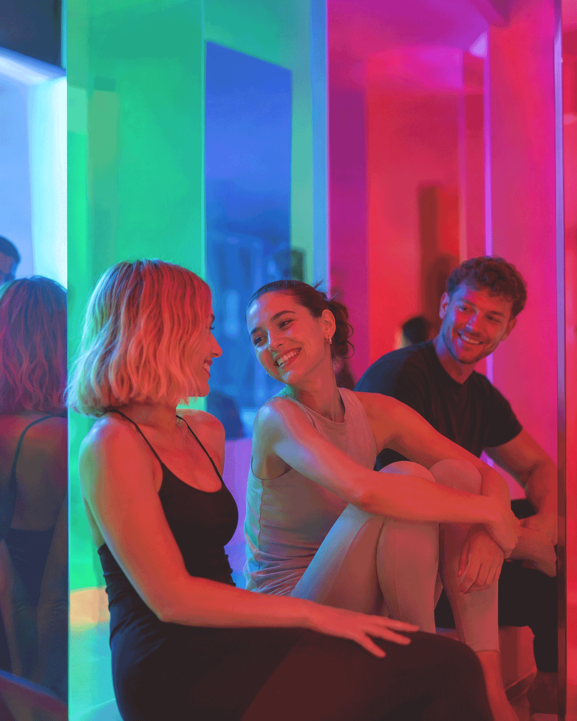 Friends laughing together under colourful light